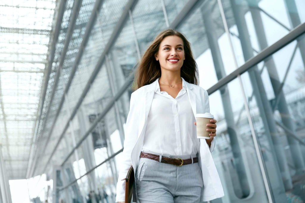 Woman walking with a casual business outfit and a cup of coffee