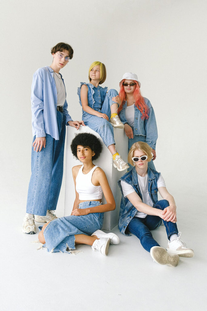 Five teenagers wearing a variety of casual outfits. The group includes a mix of styles such as graphic tees, denim jackets, and sporty leggings.